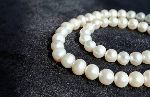 istock White pearls necklace on black flannel. 1344507458