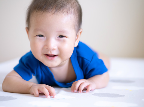 close up smiling of adorable Asian infant baby girl for tummy time or play time , happy emotion expression of baby
