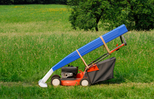 Orange lawn mower and big razor resting in backyard