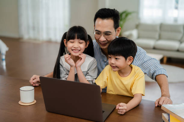 istock Asian child attending to online class from home with father. 1344520437