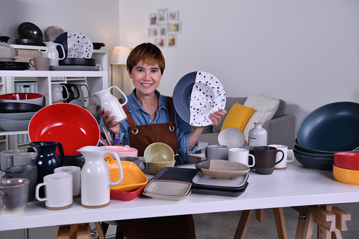 Mature Asian woman entrepreneur/ Business owner showing her clay ceramic product and working at home