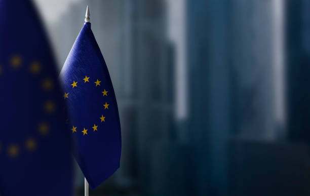 kleine flaggen der europäischen union auf einem verschwommenen hintergrund der stadt - europäische union stock-fotos und bilder