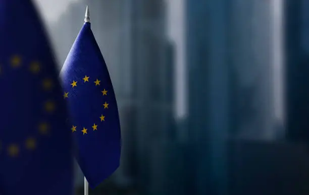 Small flags of European Union on a blurry background of the city.