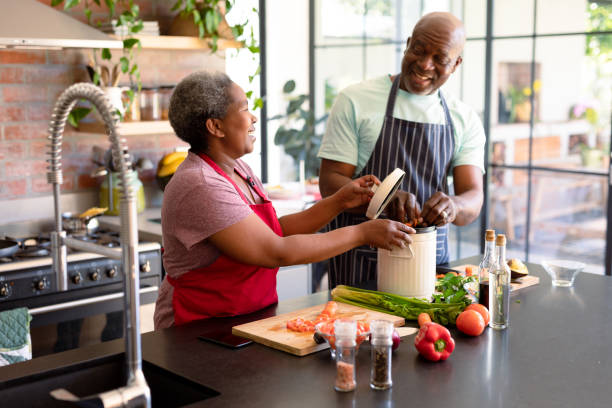 Happy african american senior couple cooking together in kitchen stock photo