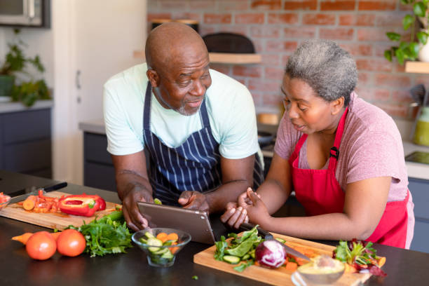 istock Happy african american senior couple cooking together in kitchen, using tablet 1344526249