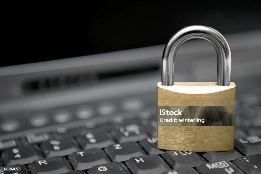 A locked padlock on top of a computer keyboard Padlock standing on a black laptop keyboard. Accessibility Stock Photo