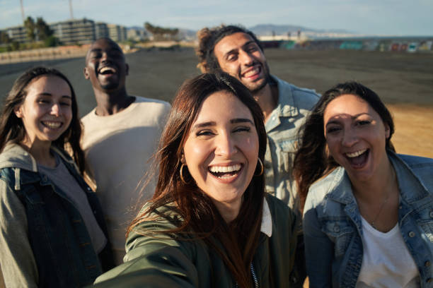istock Funny group of fiends taking selfies at sunset. 1344527005