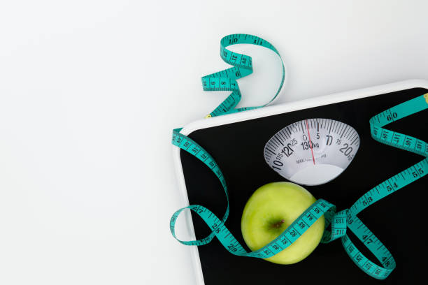 istock Weight scale and measure tape with fresh apple on white background with copy space , Weight loss or healthy diet control to a slim healthy body concept 1344527193