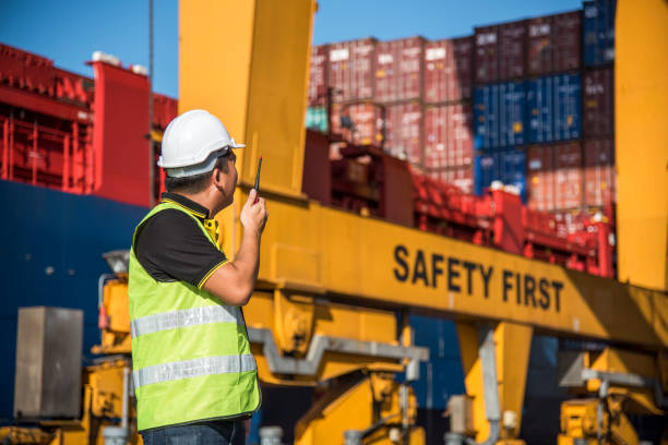 istock worker working with radio transceiver for controlling crane to loading container box to container ship 1344530817