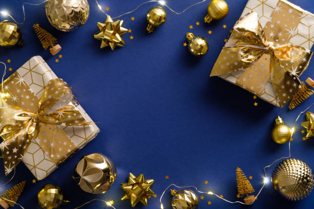 istock Luxury Christmas frame border. Flat lay gift boxes, golden decorations, garland lights on blue background. Top view, flat lay. New Year greeting card template, Xmas postcard mockup 1344535269