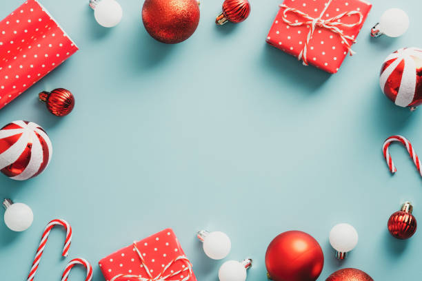 istock Vintage Christmas frame with balls decoration, gift boxes, candy canes on blue background. Retro style Christmas card template. Flat lay, top view. 1344536452