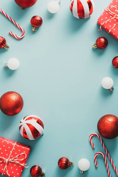 istock Vintgae Christmas frame with striped red decorations, gift boxes, candy canes on pastel blue background. Christmas poster template. Retro style greeting card. 1344536454