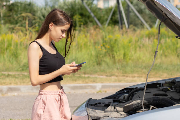 istock car problems,woman with a broken auto on the road,help is called by phone 1344537501