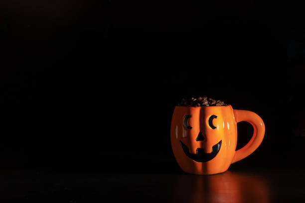 Halloween coffee,pumpkin cup with coffee beans on a black background with a place for text Halloween coffee,pumpkin cup with coffee beans on a black background with a place for text gross coffee stock pictures, royalty-free photos & images