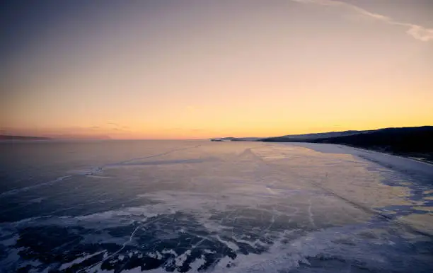 Photo of Frozen Lake Baikal, hummocks. Beautiful winter landscape with clear smooth ice near rocky shore. The famous natural landmark Russia. Blue transparent ice with deep cracks