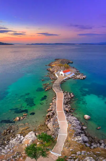 Photo of Little church of Agios Isidoros in the sea over the rocks, Chios island, Greece.