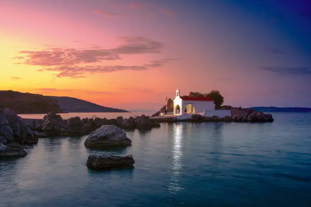 Photo of Little church of Agios Isidoros in the sea over the rocks, Chios island, Greece.