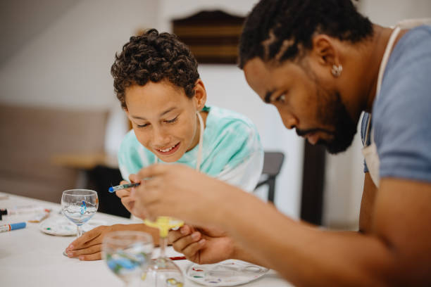 istock Father and son decorating wine glasses together 1344550613