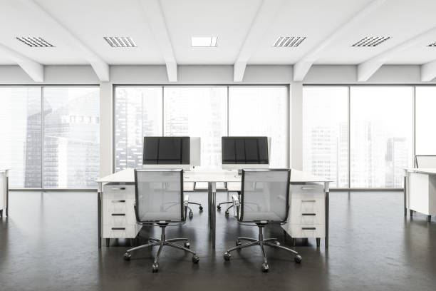 istock Closeup of white office space with desks and panoramic windows 1344551942