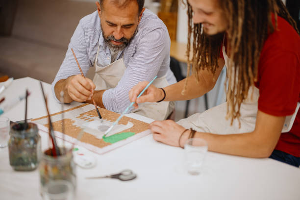 istock Mature father and teenage son preparing base for scale model making 1344552959