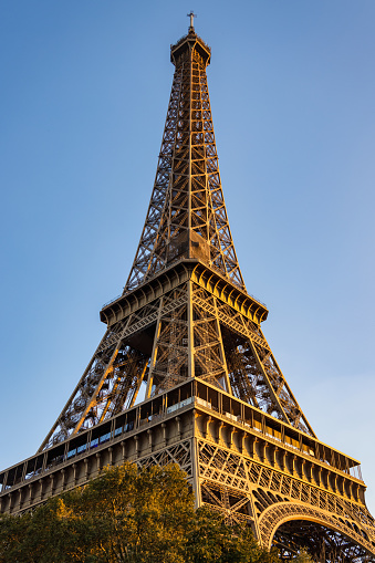 Iconic Eiffel Tower in Paris from below against blue summer sky in warm late afternoon sunlight. Eiffel Tower, Champ de Mars, 7th Arrondissement, Paris, France, Europe