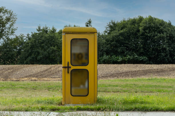 市外の牧草地に古い黄色の電話ブース - pay phone ストックフォトと画像