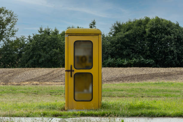 도시 외곽의 초원에 있는 오래된 노란색 전화 부스 - telephone booth 뉴스 사진 이미지