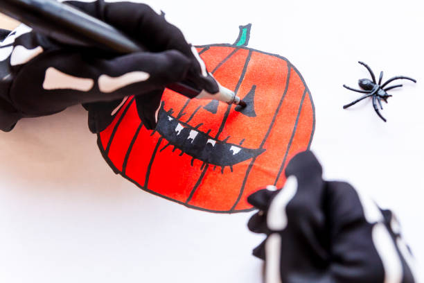 istock Hands drawing a toothy pumpkin for Halloween, close-up. 1344555684