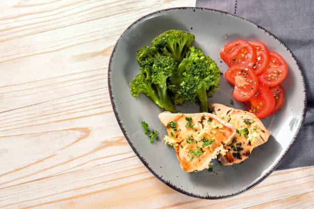 ломтики тунца с брокколи и помидорами на серой тарелке и светлом деревянном столе, здоровая еда для похудения с кетогенной или низкоу�глево� - tuna steak fillet food plate стоковые фото и изображения