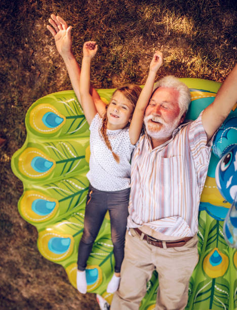 feliz familia multigeneracional disfrutando en la fiesta del jardín al atardecer - child swing swinging spring fotografías e imágenes de stock