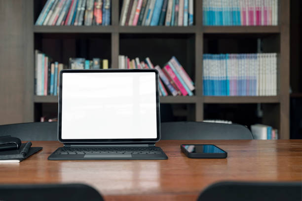 istock Blank screen laptop and gadget on wooden table in library room. 1344559051