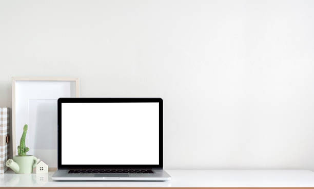 istock Mockup blank screen laptop computer, wooden frame and plant on white top table with copy space. 1344559672