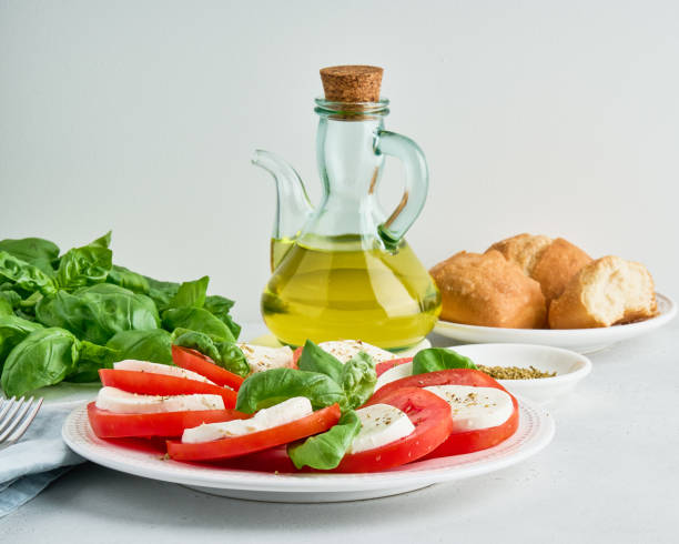 insalata caprese italiana. antipasto con mozarella, pomodori, foglie di basilico, olio d'oliva e ciabatta - mozarella sul tavolo foto e immagini stock