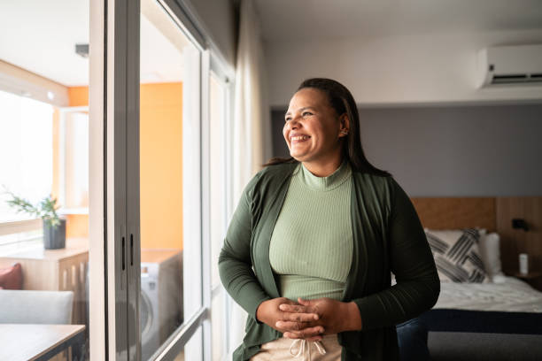 happy mature woman contemplating at home - women common 40s candid imagens e fotografias de stock