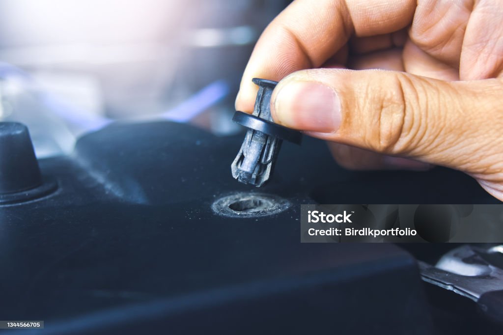 Mechanic hand installing automotive plastic fasteners Mechanic hand installing automotive plastic fasteners to the car body in the auto repair garage Rivet - Work Tool Stock Photo