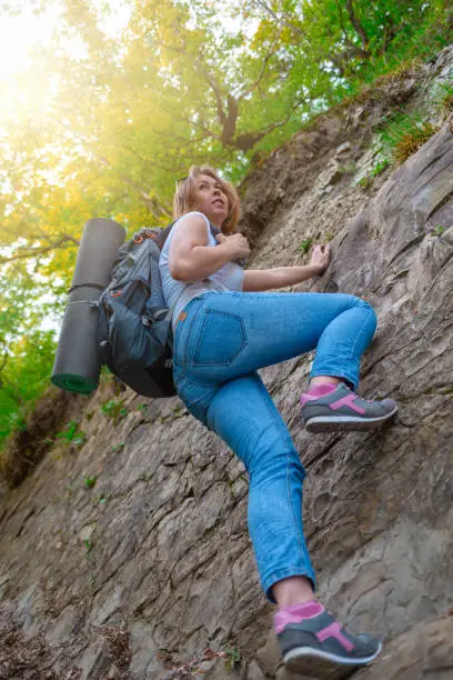 Photo of A young woman is engaged in rock climbing. Leisure and active sports. Light. Bottom view