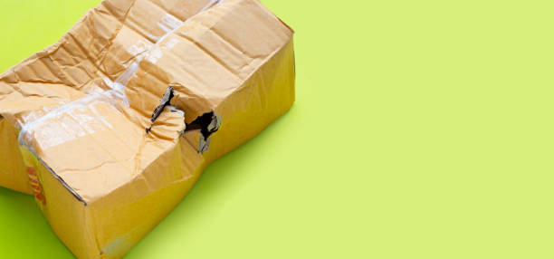 istock Damaged cardboard box with hole on green background. 1344571077