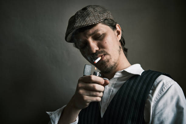 istock Young guy lights a cigarette, dressed in a retro style 1344573500