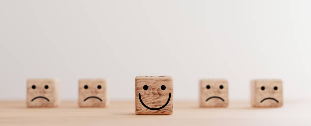 istock Smile face print screen on wooden cube block among sadness face for customer service evaluation and emotion mindset concept by 3d render. 1344575612