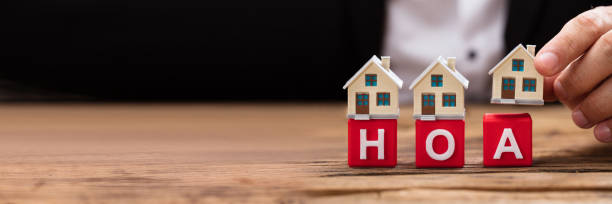 istock Businessperson placing house model over HOA blocks 1344576865