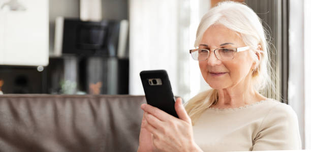Beautiful senior woman texting at home stock photo