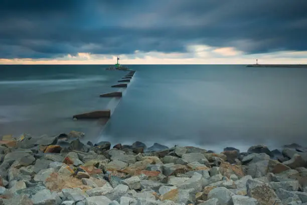 Mouth of the river Vistula in Gdansk. Long exposure seascape. Beautiful rocky breakwater on sea shore and protection walls on mouth of river.
