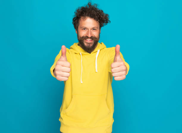 istock curly hair man with moustache smiling and making thumbs up gesture 1344584796