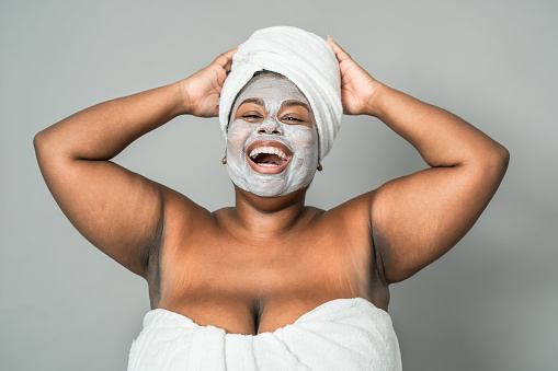 Happy curvy African woman having skin care spa day - Healthy beauty clean treatment and youth people lifestyle concept