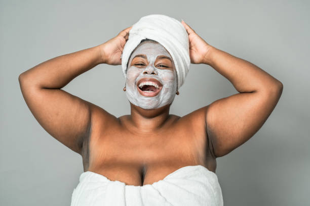 Happy curvy African woman having skin care spa day - Healthy beauty clean treatment and youth people lifestyle concept Happy curvy African woman having skin care spa day - Healthy beauty clean treatment and youth people lifestyle concept facial mask beauty product stock pictures, royalty-free photos & images