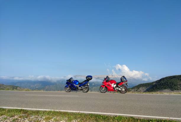 View from motorcycle driver perspective riding in Alpine landscape during sunrise