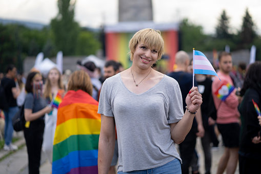 Transperson standing waving transgender flag for the rights of the LGBT+ community