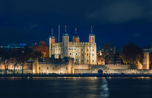 The Tower of London illuminated at night by the river Thames in London, England