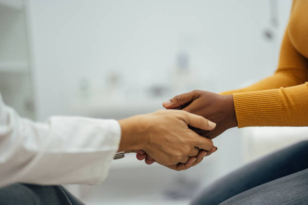 Caring doctor and woman holding hands. stock photo