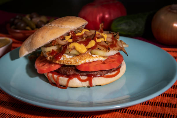 istock Hamburger with egg, tomato, cucumber, onion, ketchup and mustard, in a round bun. 1344594580